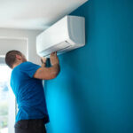 Closeup side view of a trained professional installing an indoor unit of a split AC system.